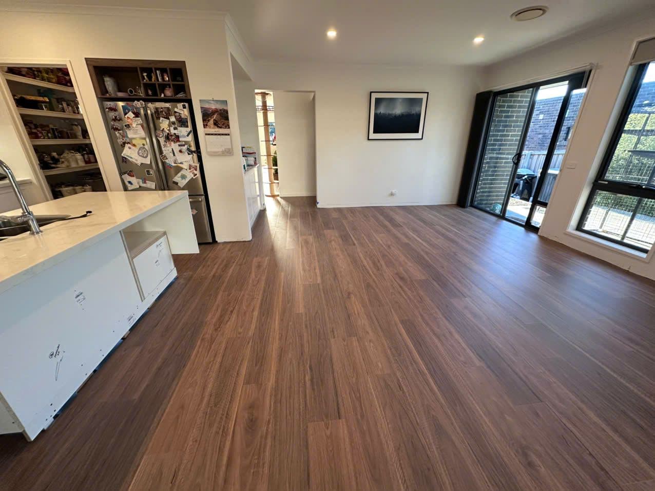 Walnut-toned planks around the island bench and walk-in pantry.
