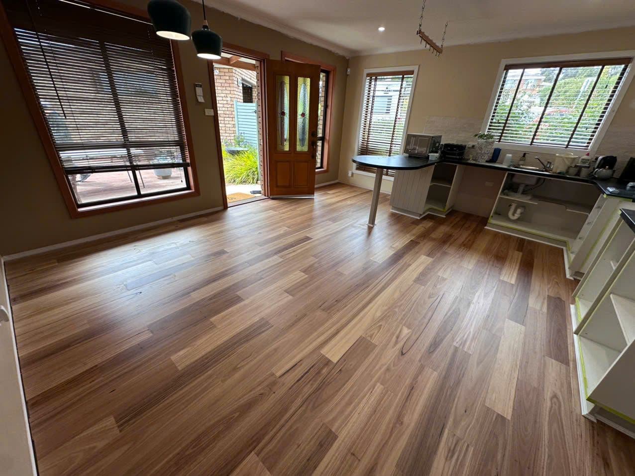 Light blackbutt-toned hybrid flooring through the cottage's open kitchen and dining area.
