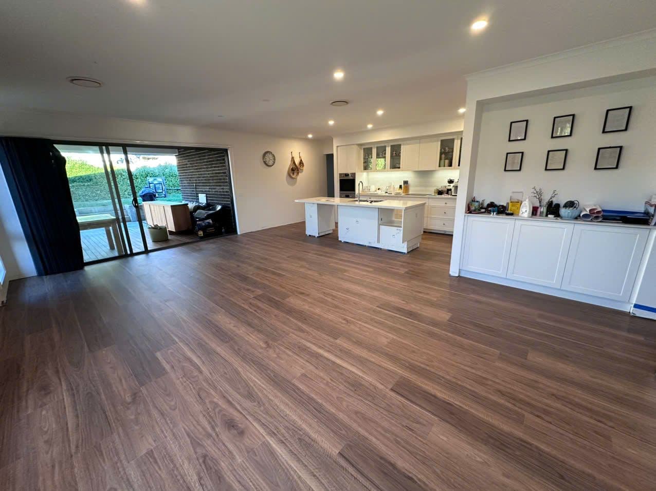 Dark walnut-toned planks flowing through the open-plan kitchen and living area.