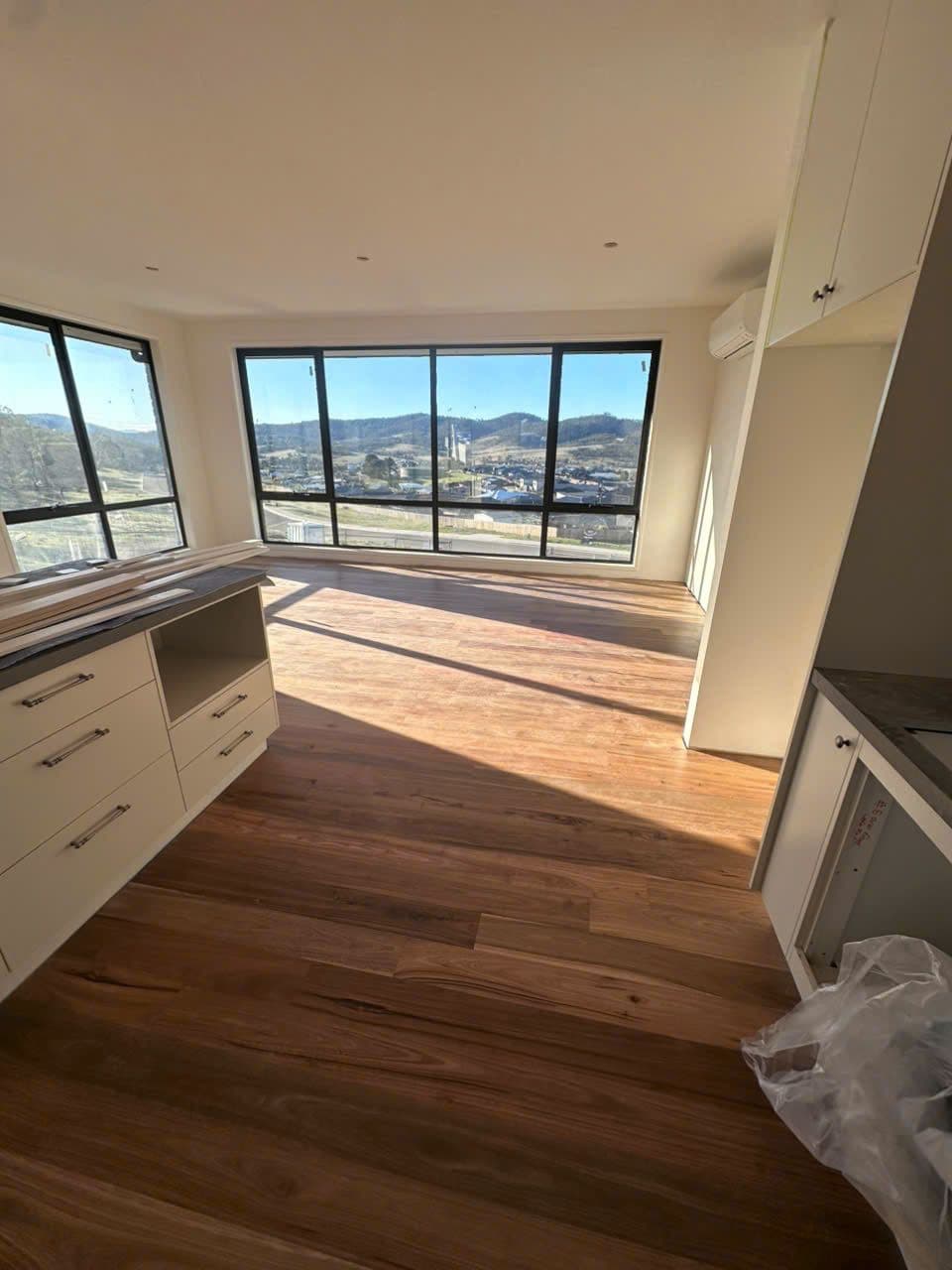 Timber boards in the kitchen corner, hills and rooftops through the corner windows.